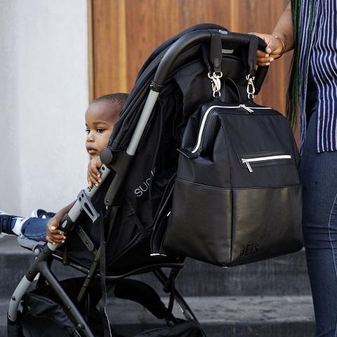 Cute afro-american toddler in a stroler. Diaper bag hanging from the handle.