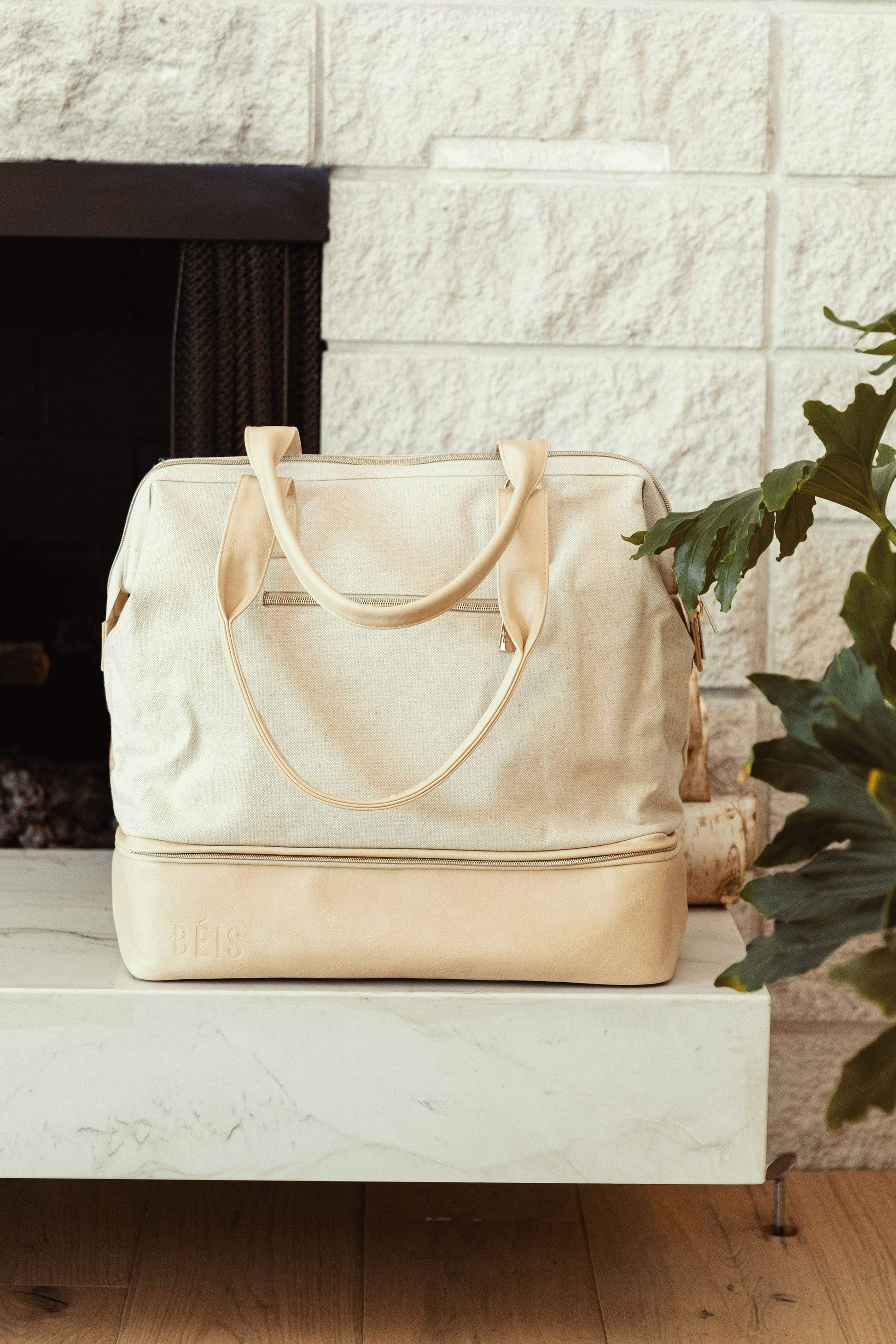 BEIS by Shay Mitchell The Convertible Mini Weekender in Beige near fireplace